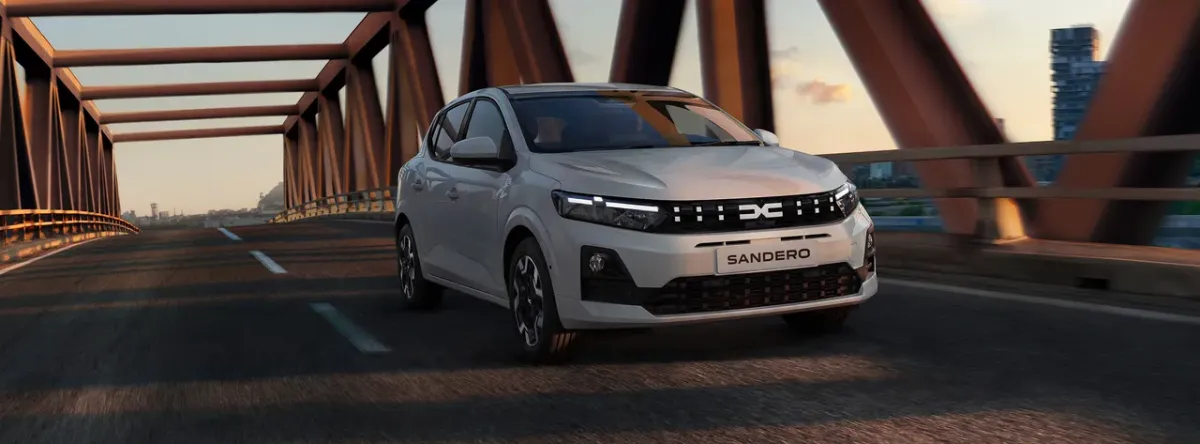 Dacia Sandero restylée blanche roulant sur un pont métallique en ville