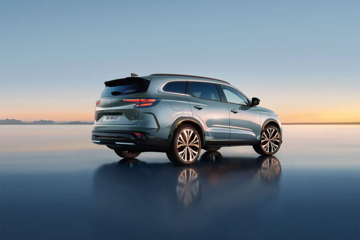 Renault Espace gris vert vu de trois quarts arrière sur un sol réfléchissant au coucher du soleil
