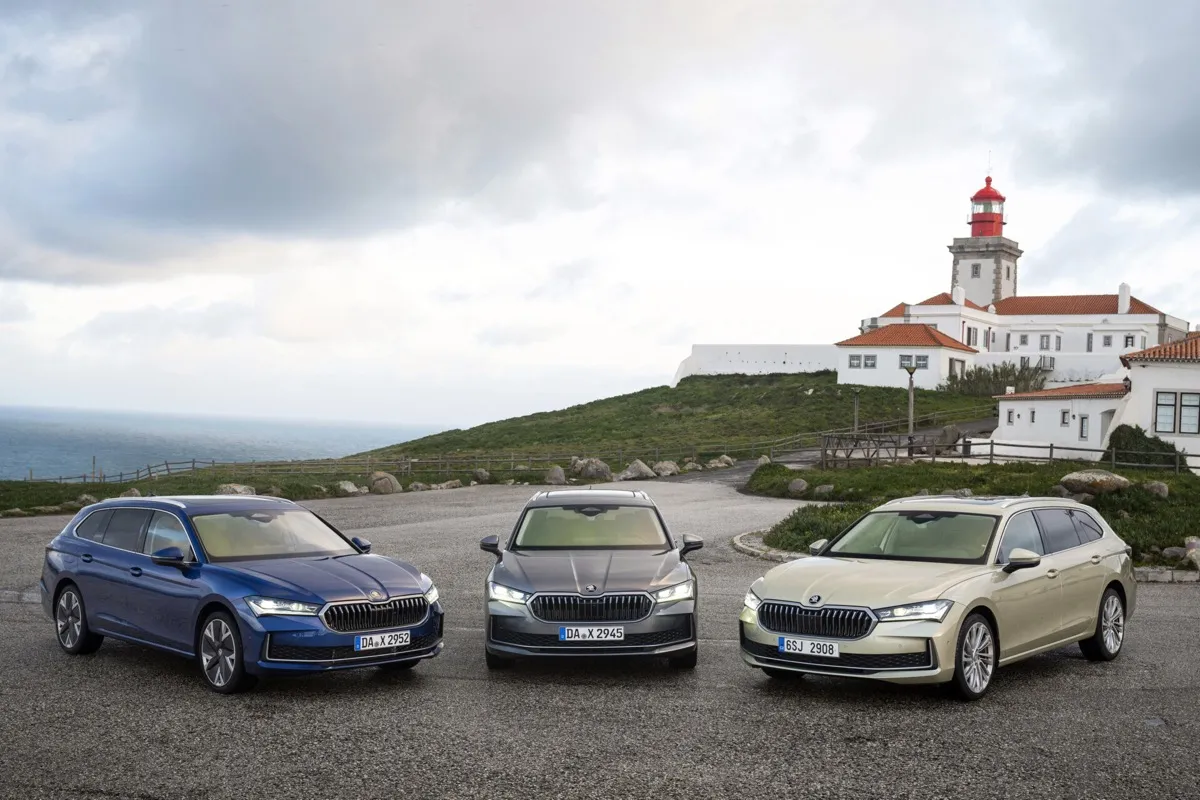 Trois Skoda Superb Combi bleue, grise et beige garées devant un phare au bord de l’océan