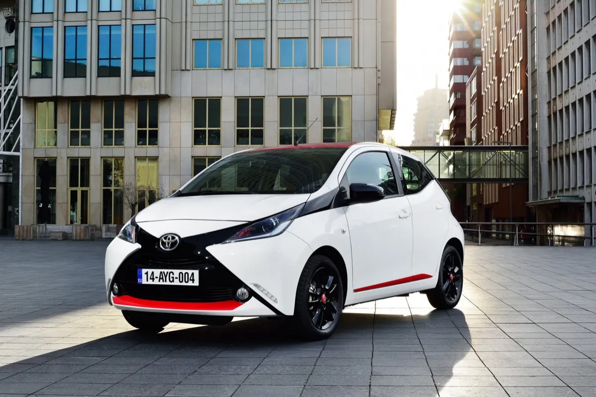 Toyota Aygo de deuxième génération blanche et noire garée sur une place pavée en ville