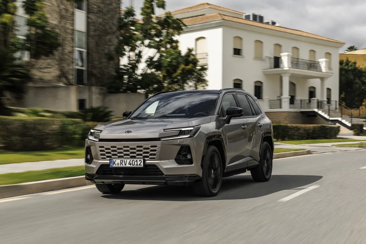 Nouveau Toyota RAV4 Plug-in Hybrid gris bronze roulant devant une villa blanche