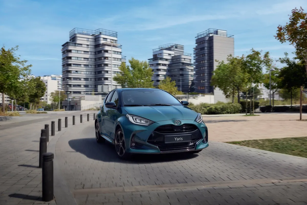Toyota Yaris Hybrid bleu-vert roulant dans une rue bordée d’immeubles