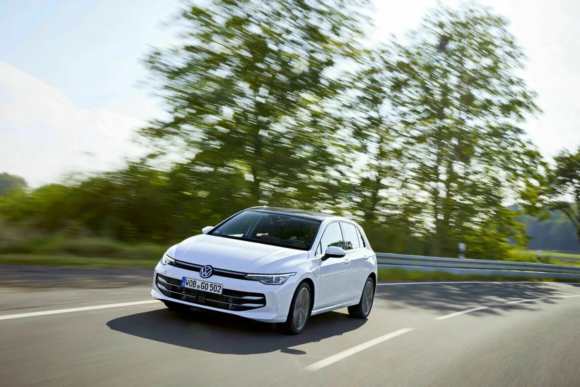 Volkswagen Golf eHybrid blanche roulant sur une route de campagne bordée d’arbres
