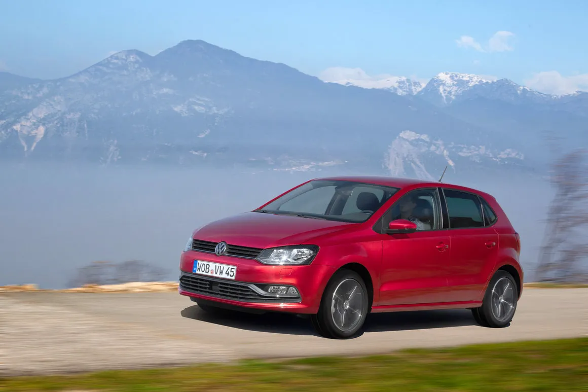Volkswagen Polo de cinquième génération restylée rouge roulant devant des montagnes enneigées