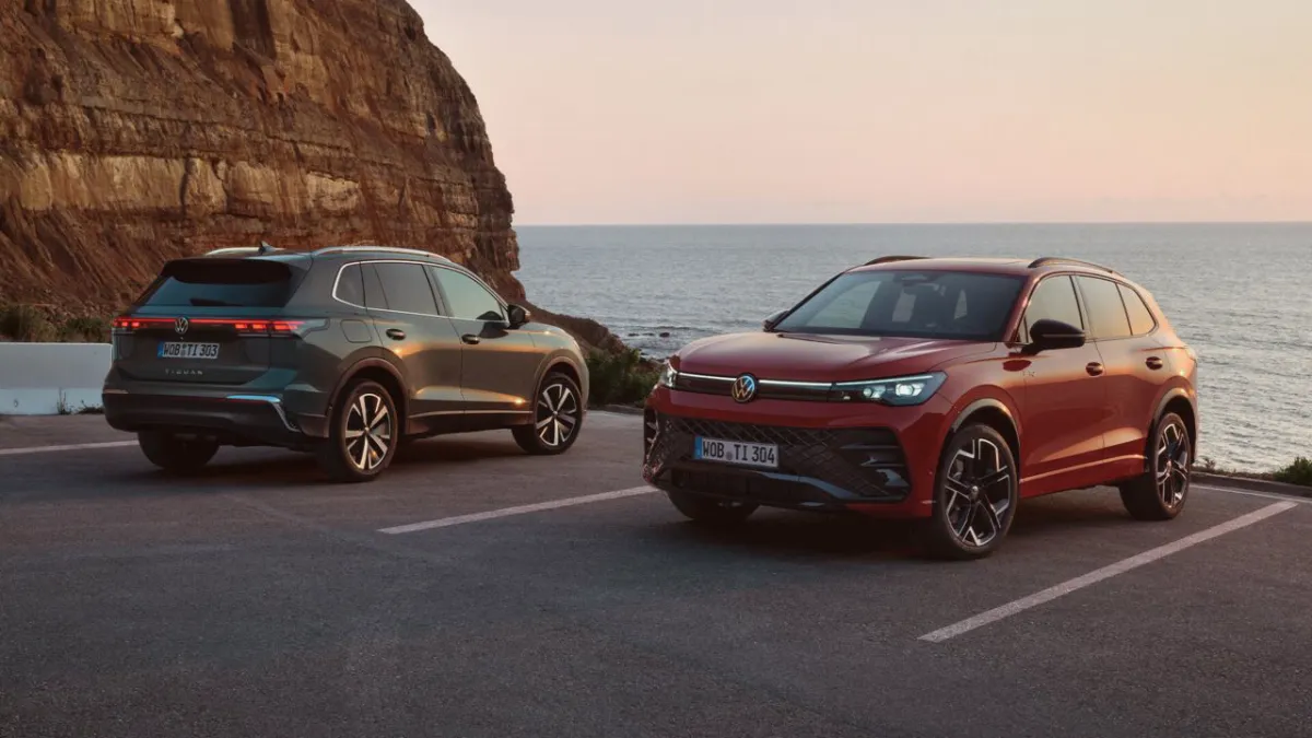 Deux Volkswagen Tiguan, un gris et un rouge, garés face à la mer au pied d’une falaise
